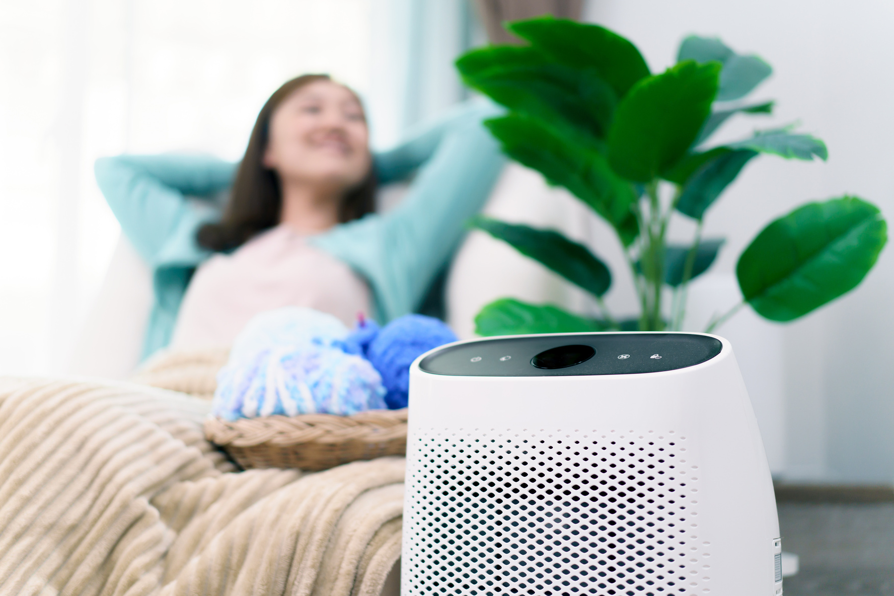 Woman relaxing in living room with an air purifier.